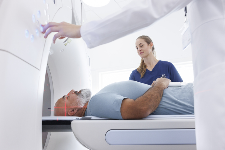 Photo shows medical professionals helping a man enter CT scanner/Getty Images
