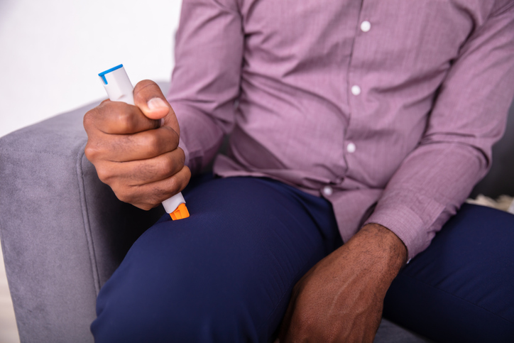 Photo shows man injecting epinephrine using auto-injector syringe/Getty Images