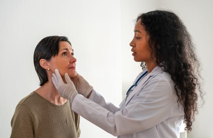 Photo shows a doctor checking a patient's lymph nodes/Getty Images