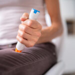 Photo shows a woman using an epinephrine injector to prevent anaphylaxis/Getty Images