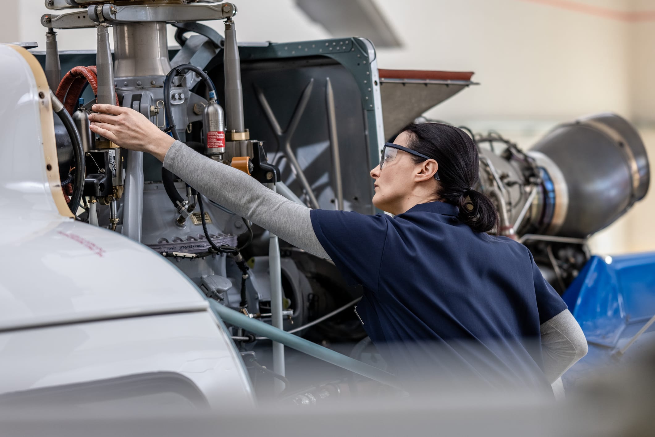 Woman wearing safety glasses working on a helicopter