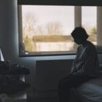 Side view of a woman sitting in her bedroom