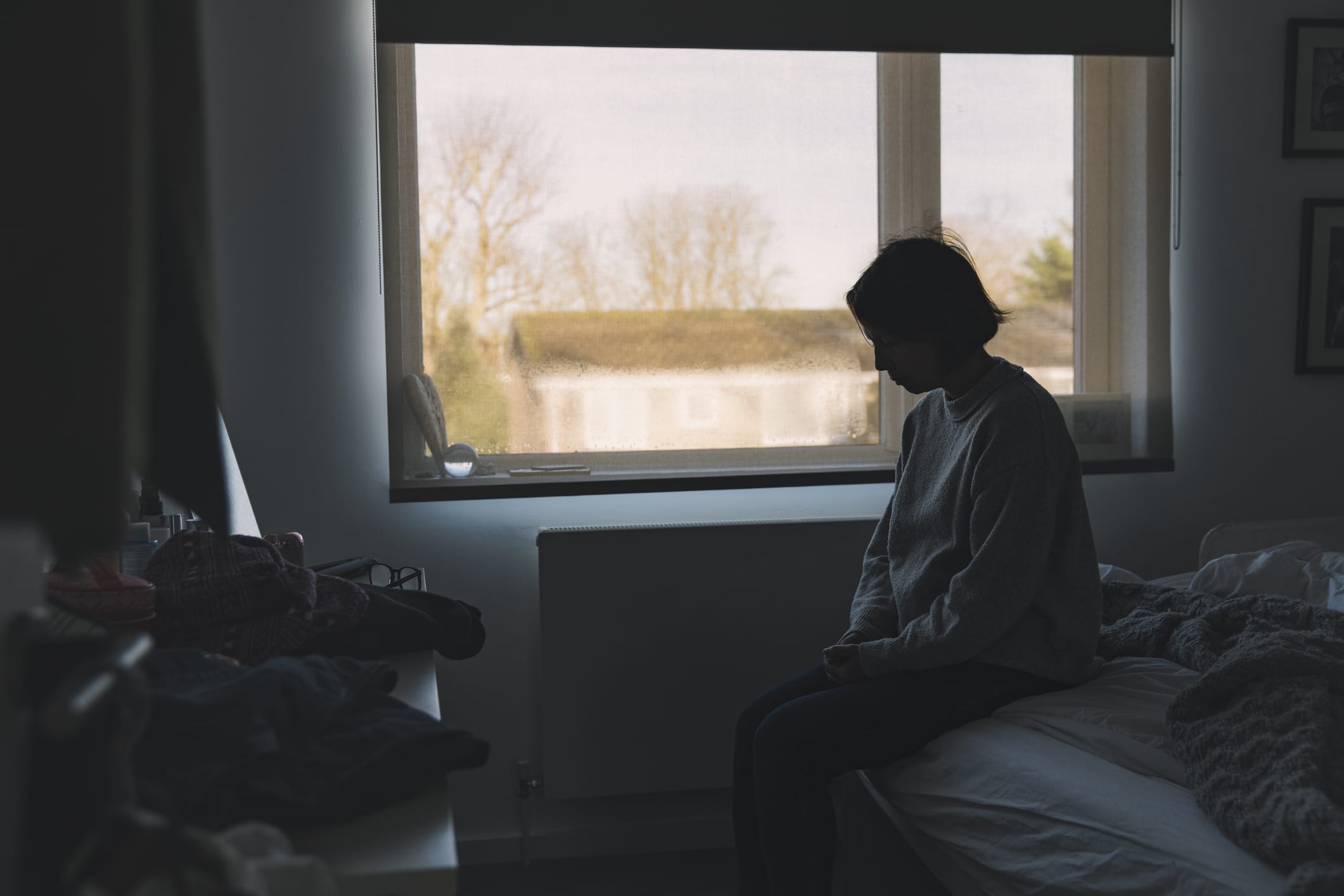 Side view of a woman sitting in her bedroom