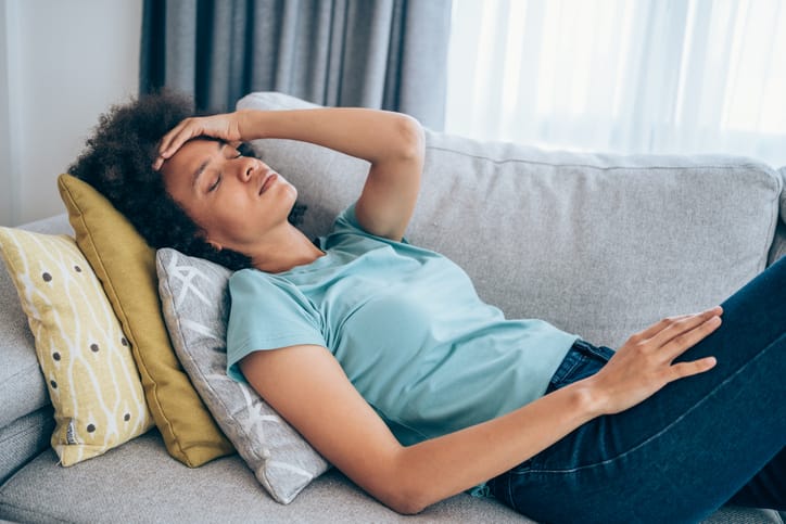 Tired woman lying down on couch