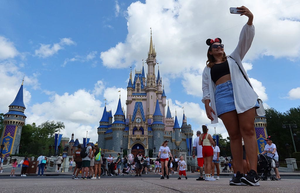 A woman takes a selfie before Cinderella's Castle at the Magic Kingdom Park at Walt Disney World
