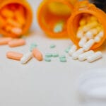 Pills with open pill bottles on the kitchen counter.
