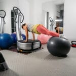 Woman training with a fitness ball on a power plate in the gym.