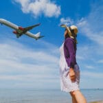 Woman watching an airplane passing by near the beach
