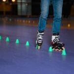 Partial view of man in roller skates skating on roller rink with cones