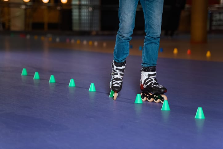 Partial view of man in roller skates skating on roller rink with cones