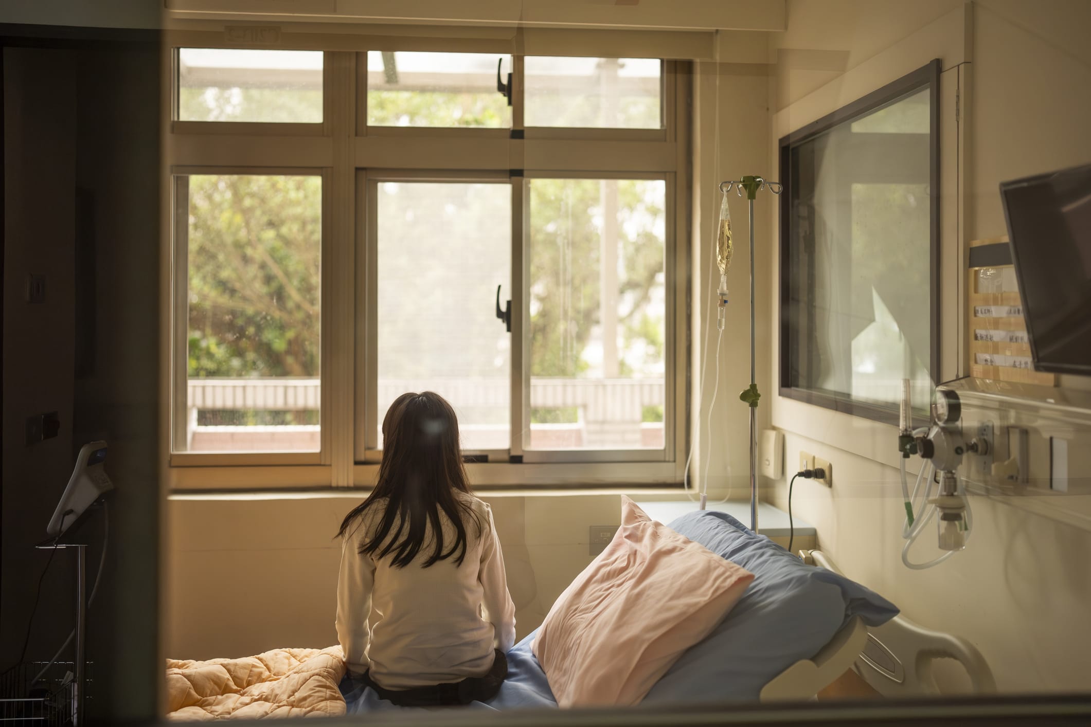 Back view of girl sitting on hospital bed