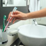 Close-up of a woman picking up a toothbrush to brush teeth