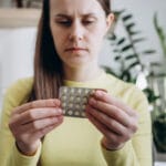 Woman looking at packet of birth control pills