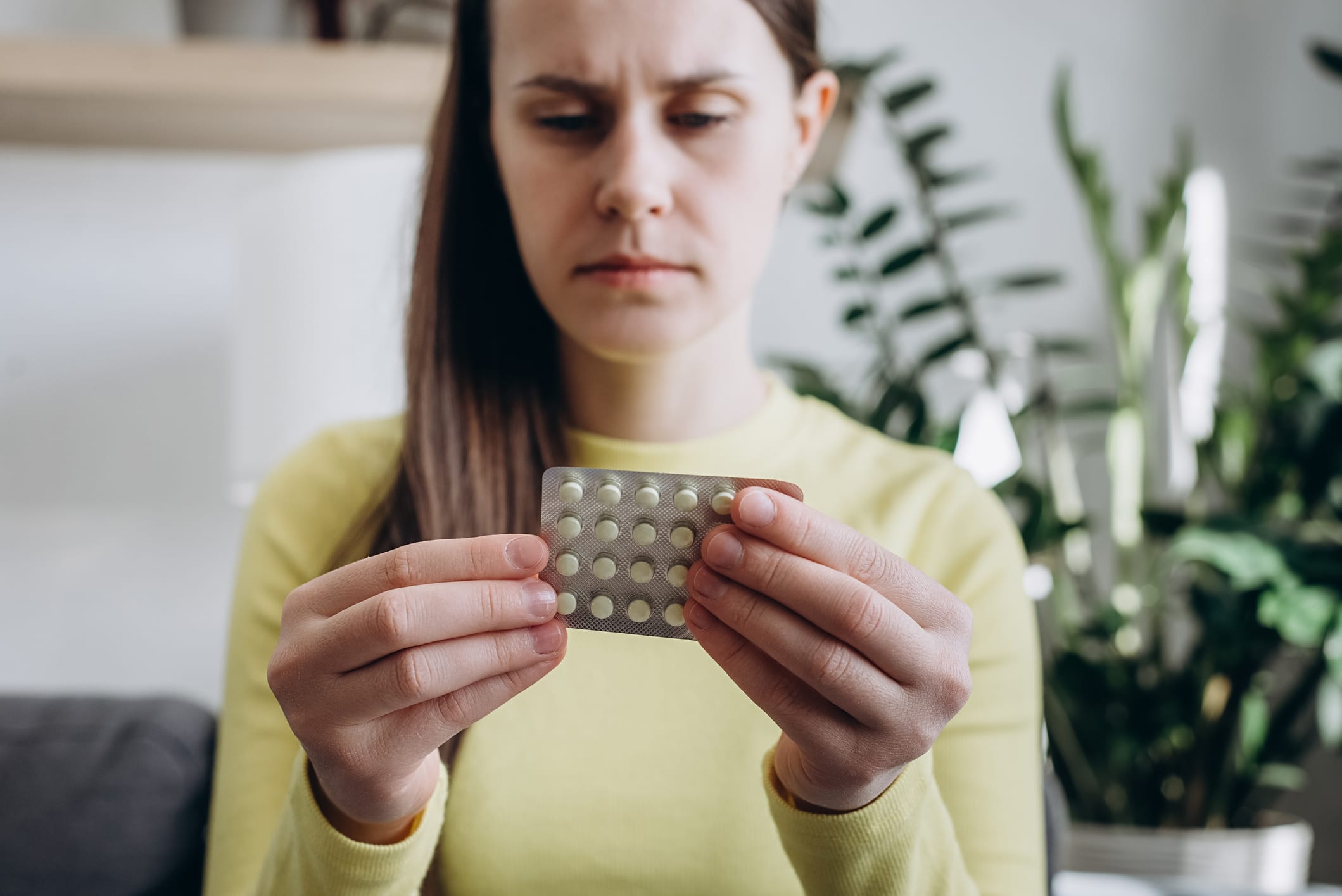 Woman looking at packet of birth control pills