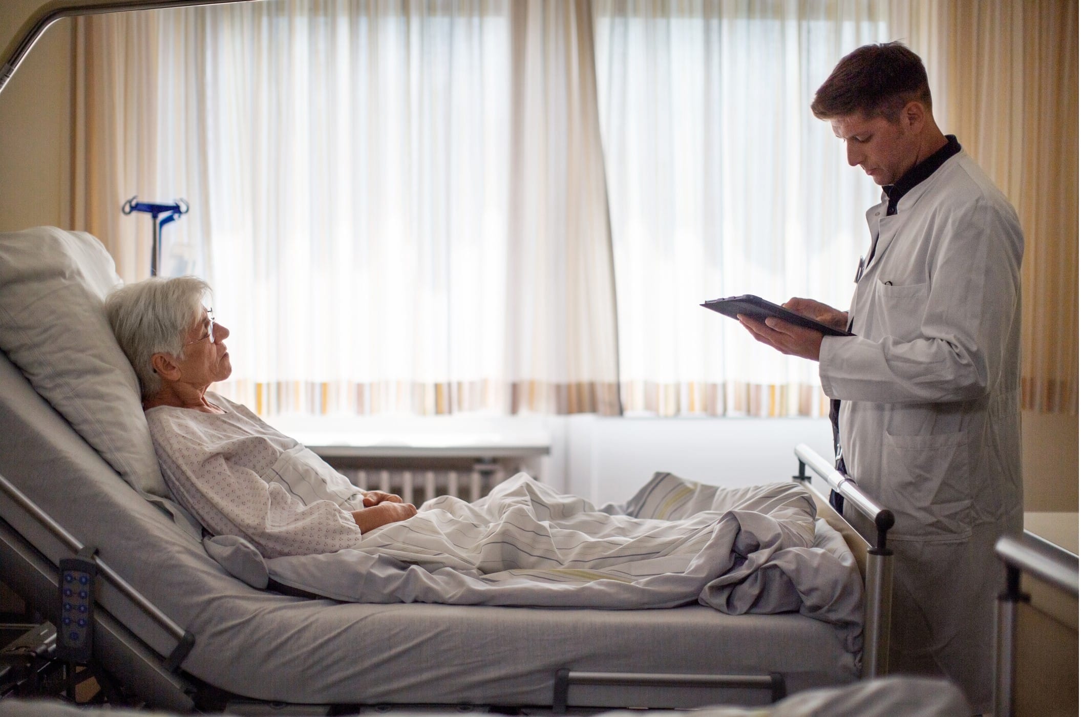Elderly woman in a hospital bed speaking with doctor