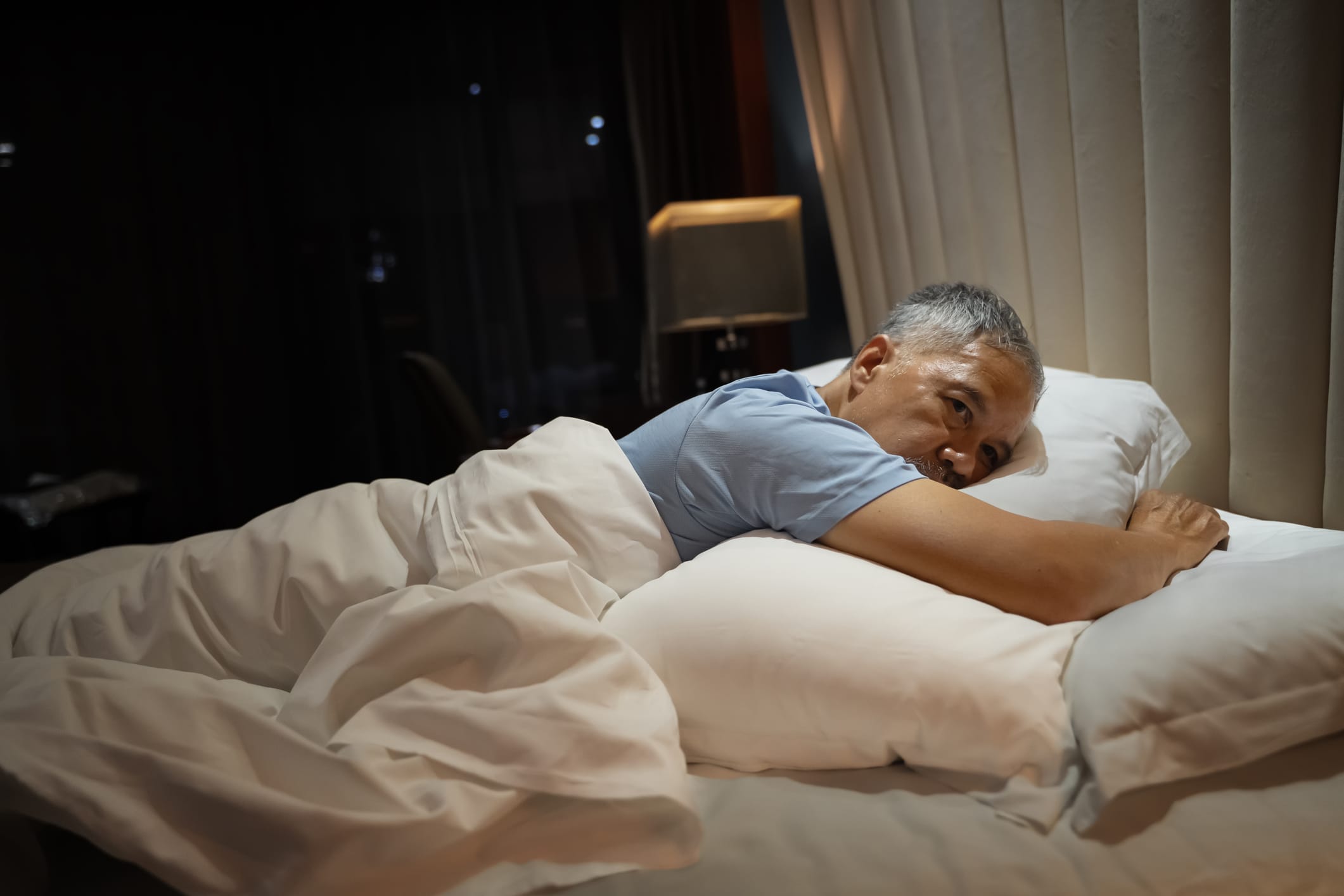 Older man lying awake in bed