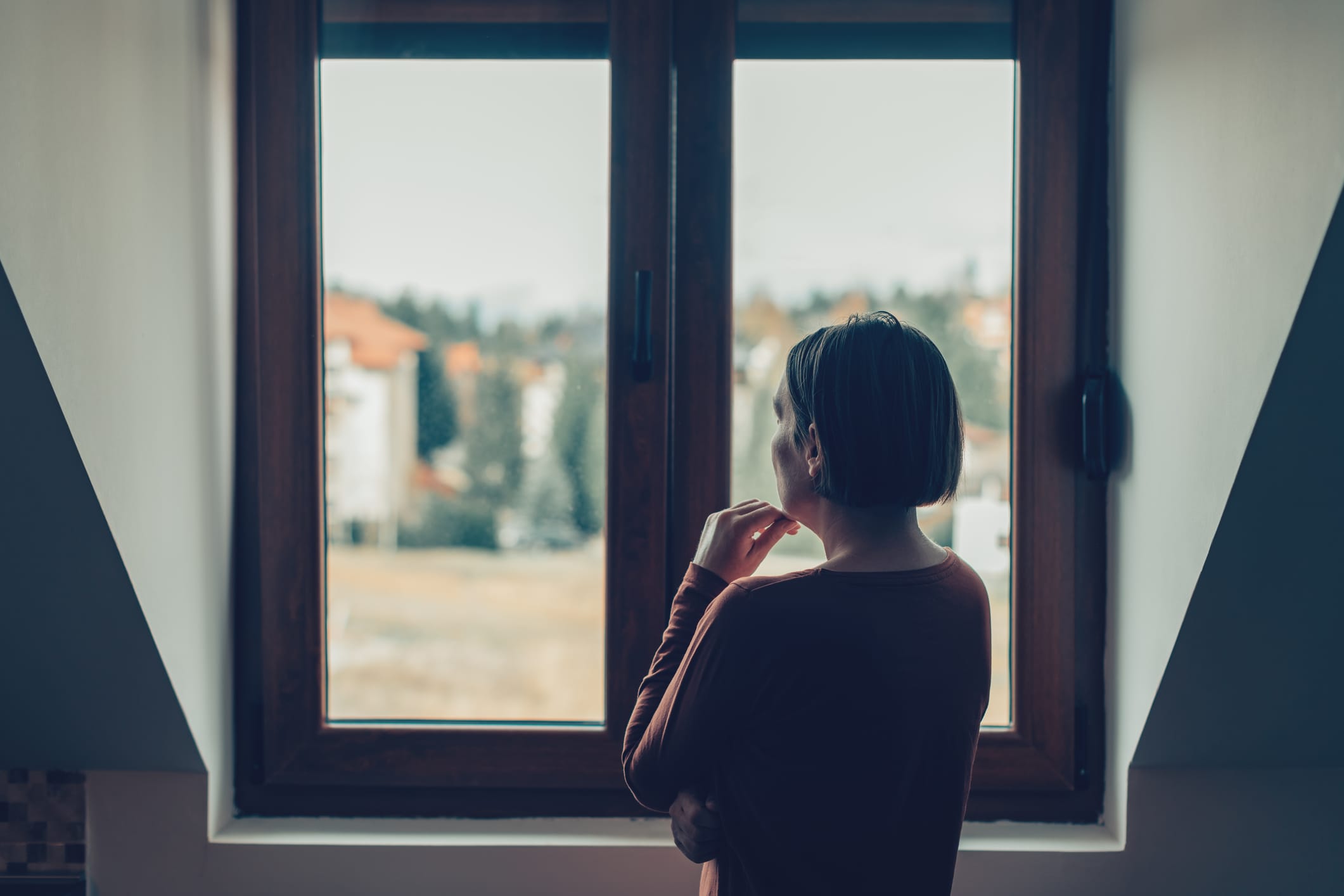 Sad woman looking out of the window in loft apartment