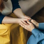 Two women holding hands while sitting