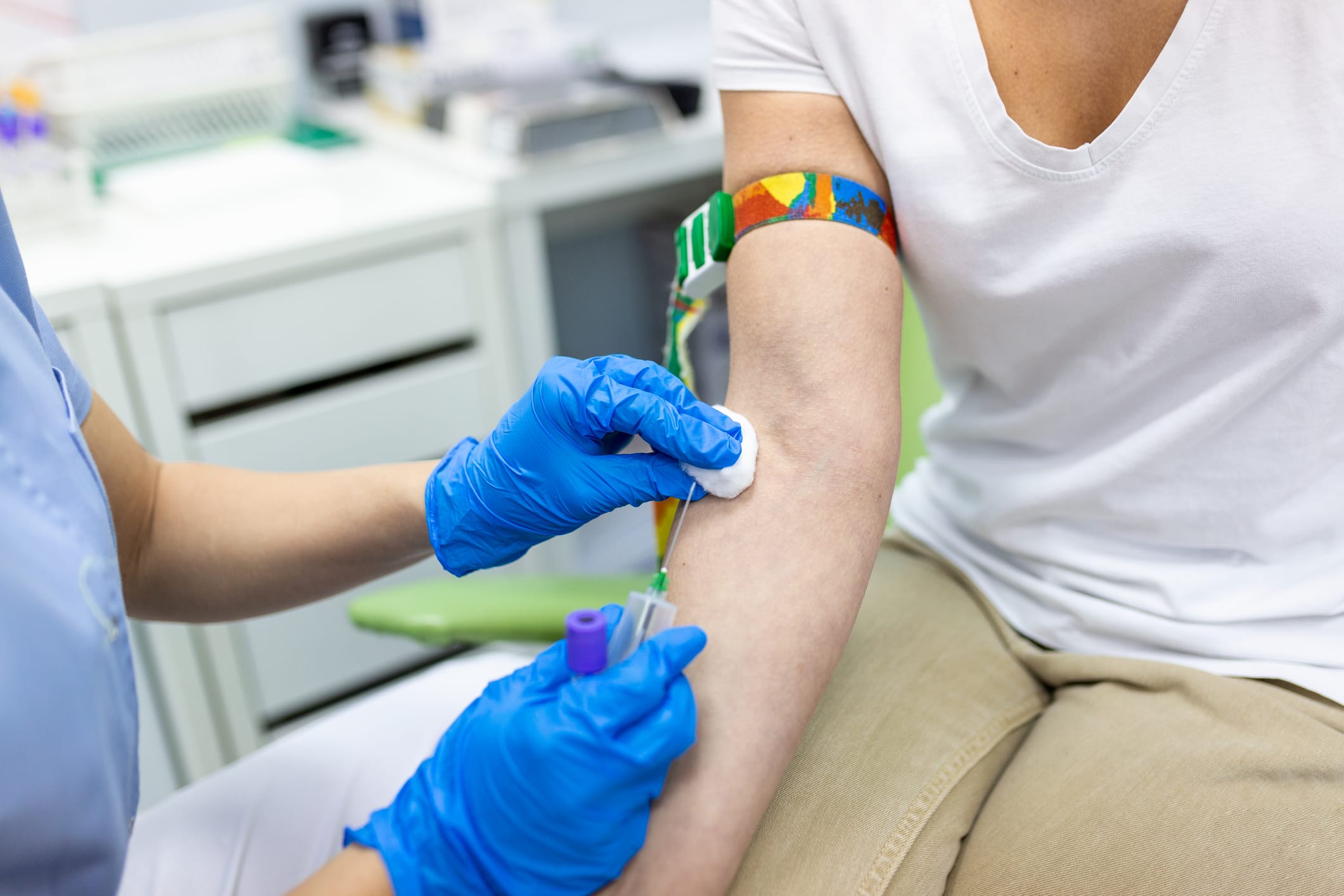 Medical technologist doing a blood draw services for patient. lab assistant with sterile rubber gloves taking blood sample from patient.