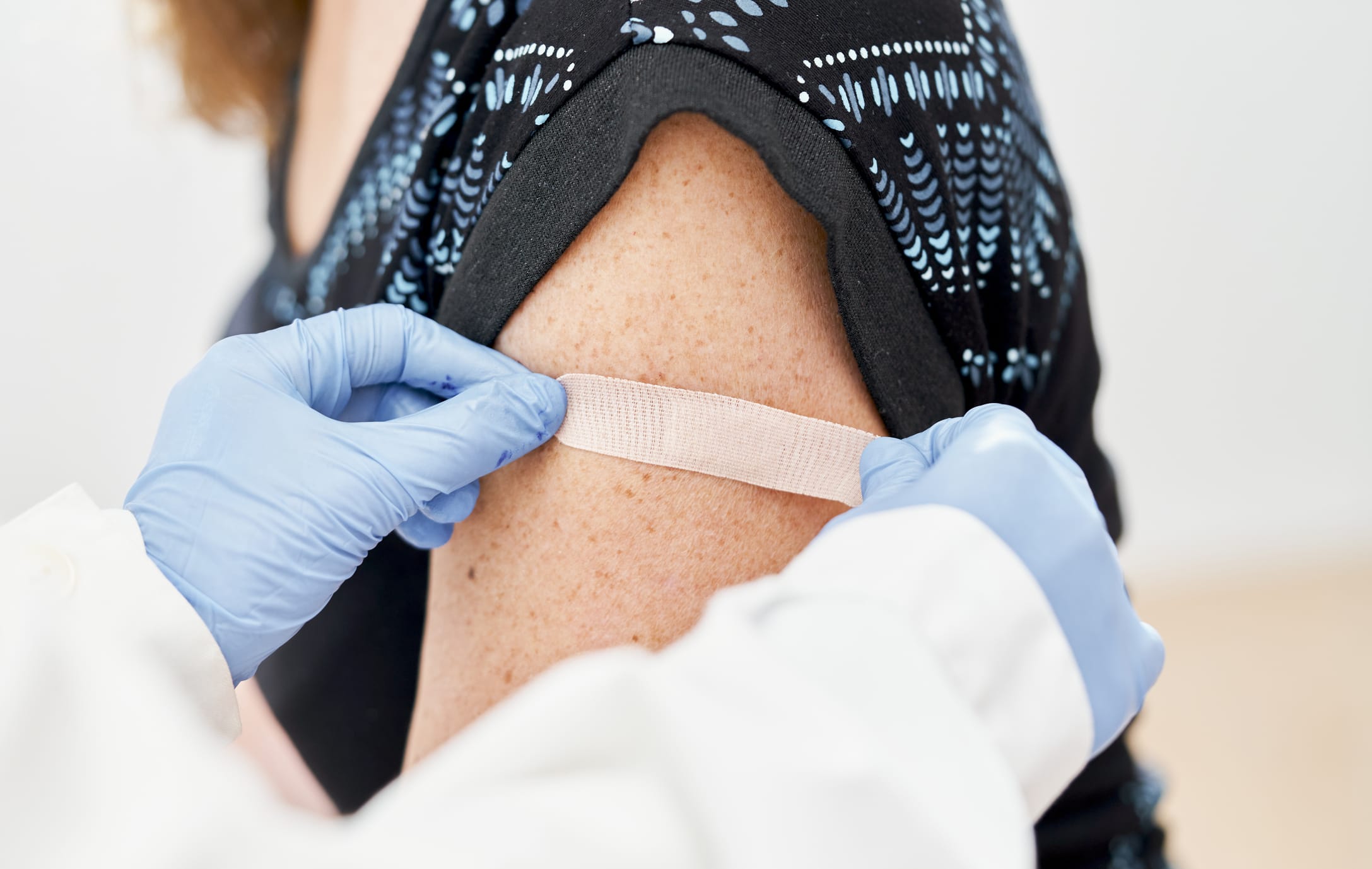 Doctor applying band-aid to his patients after receiving a vaccine