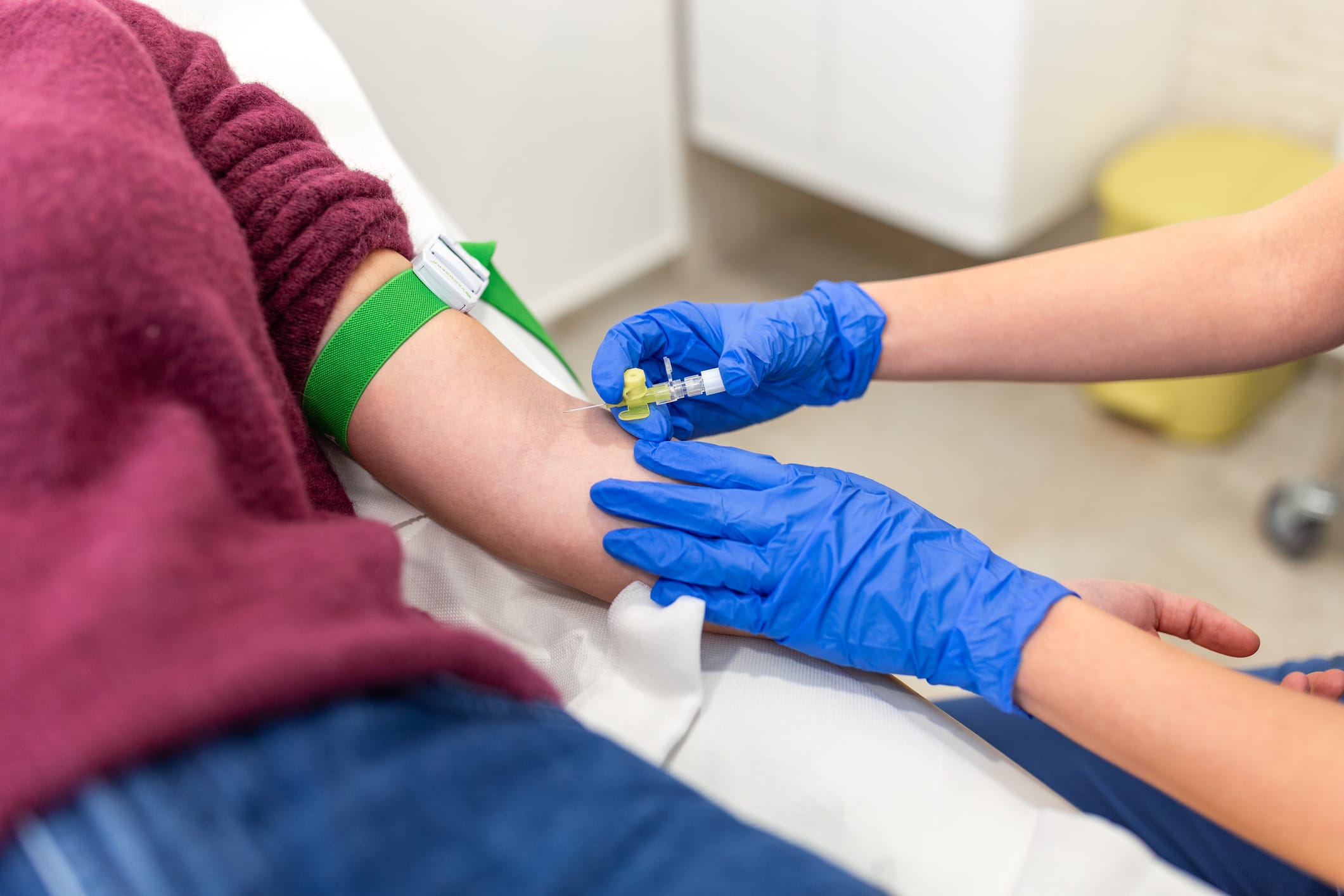 Nurse inserting IV cannula into patient arm.