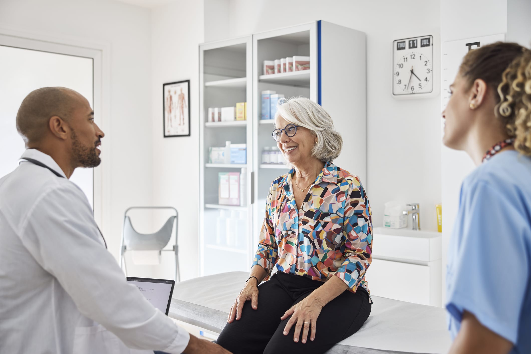 Smiling woman sitting on table and discussing with doctor at clinic.