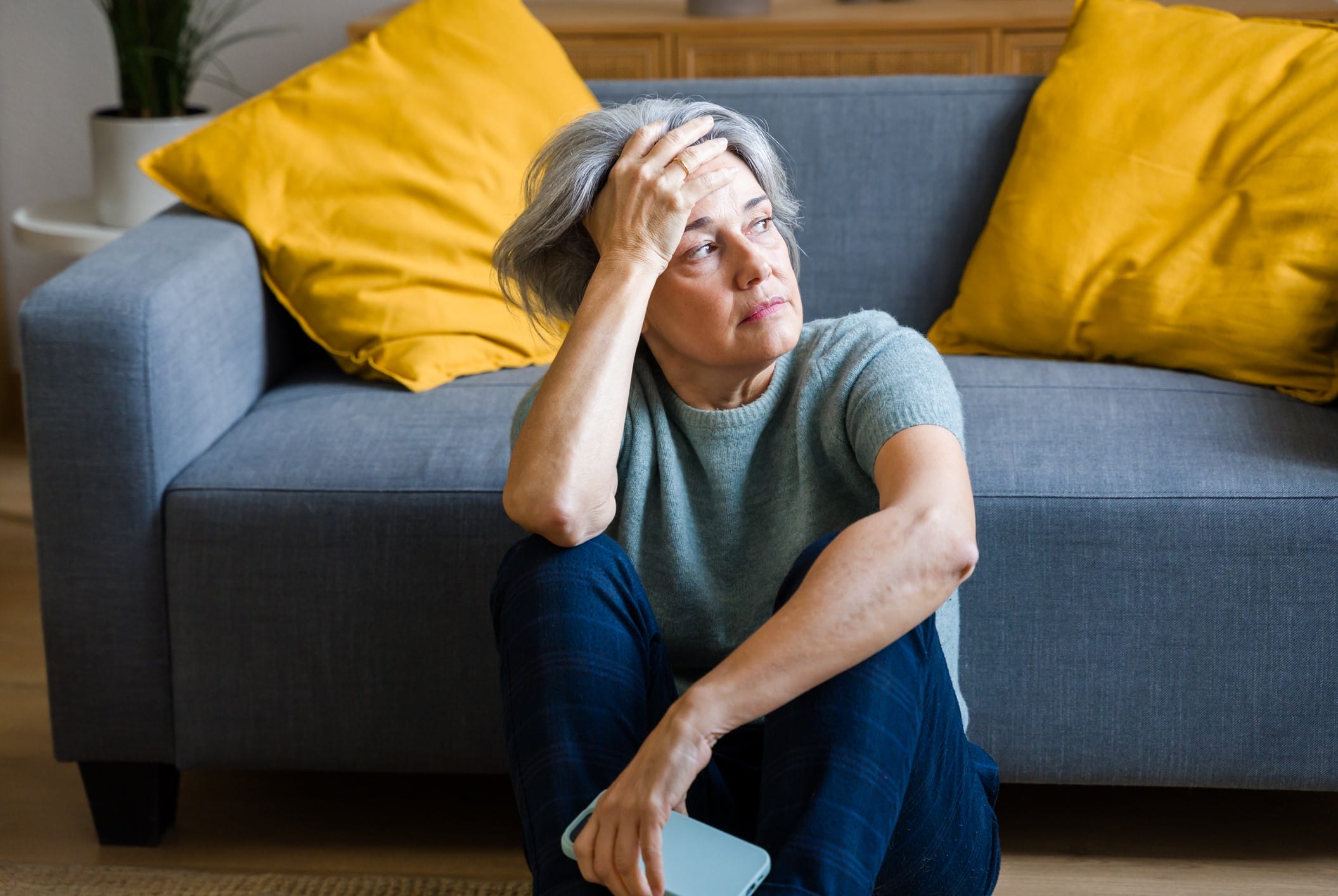 Sad woman sitting on floor in front of couch