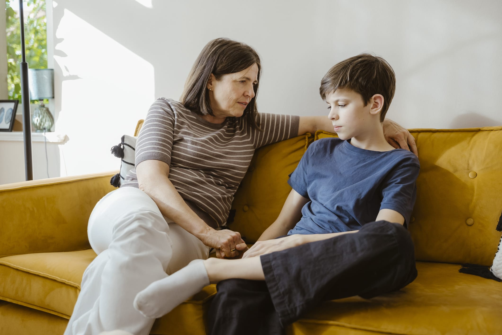Older woman sitting on ouch talking to young boy