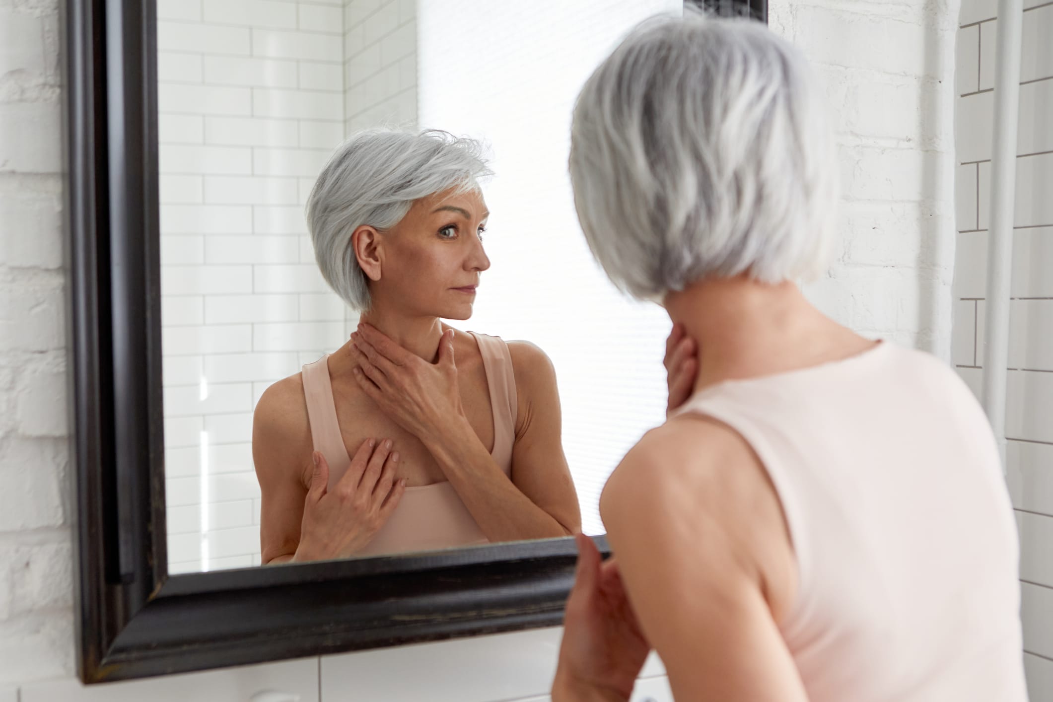 Older woman looking at skin in the mirror