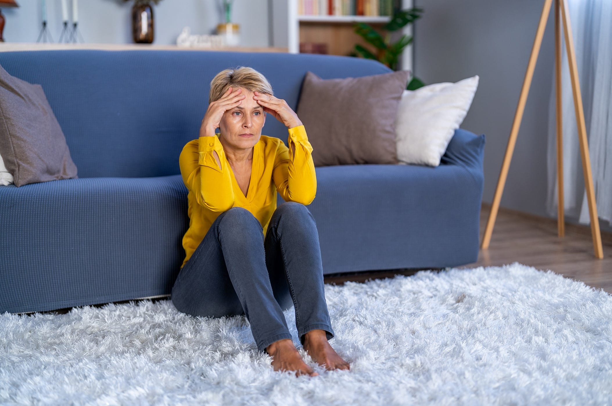 Woman with headache sitting in front of couch