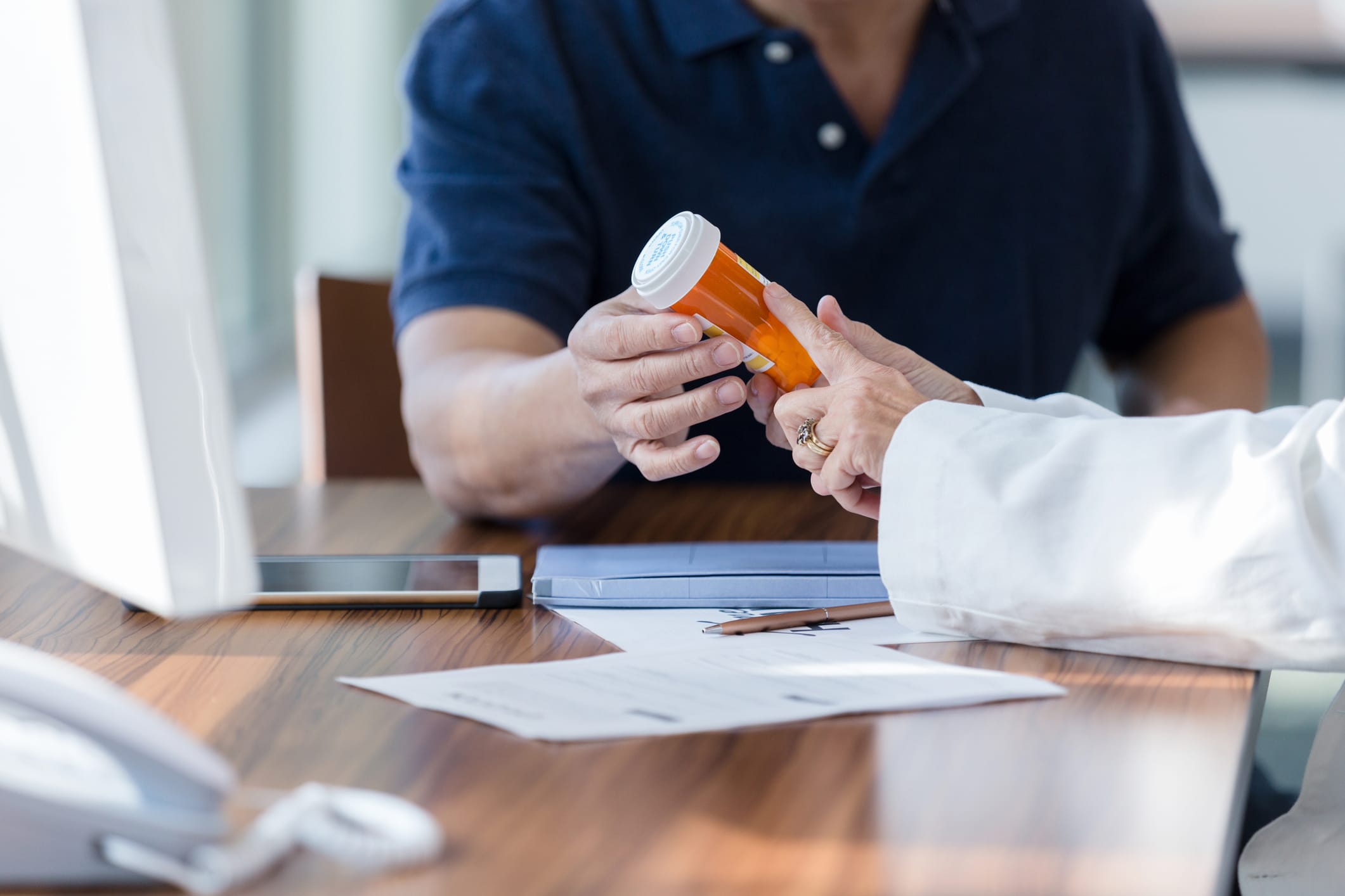 The unrecognizable female doctor warns the unrecognizable male patient about medicine side effects