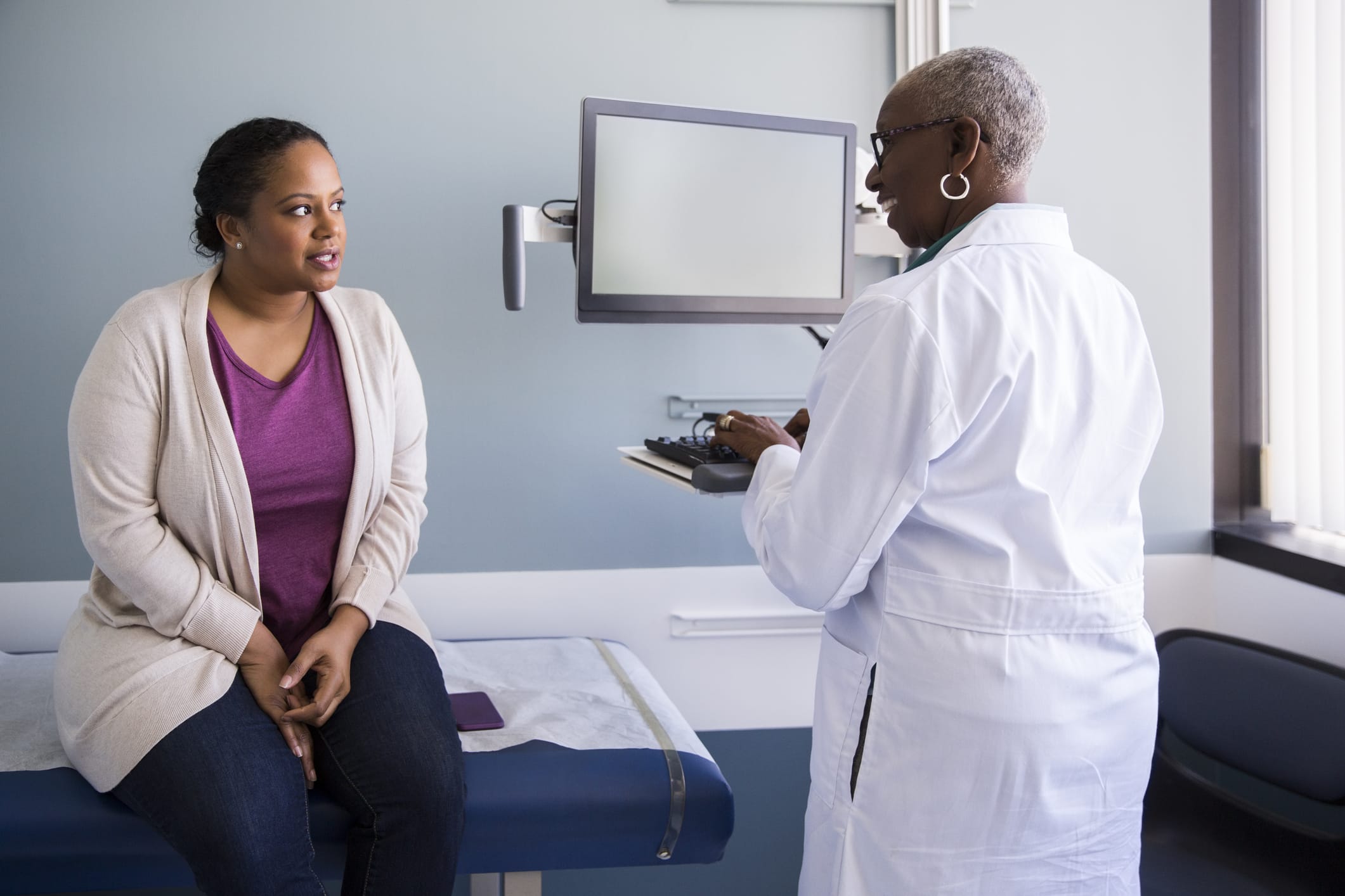 Smiling senior doctor talking to patient in hospital