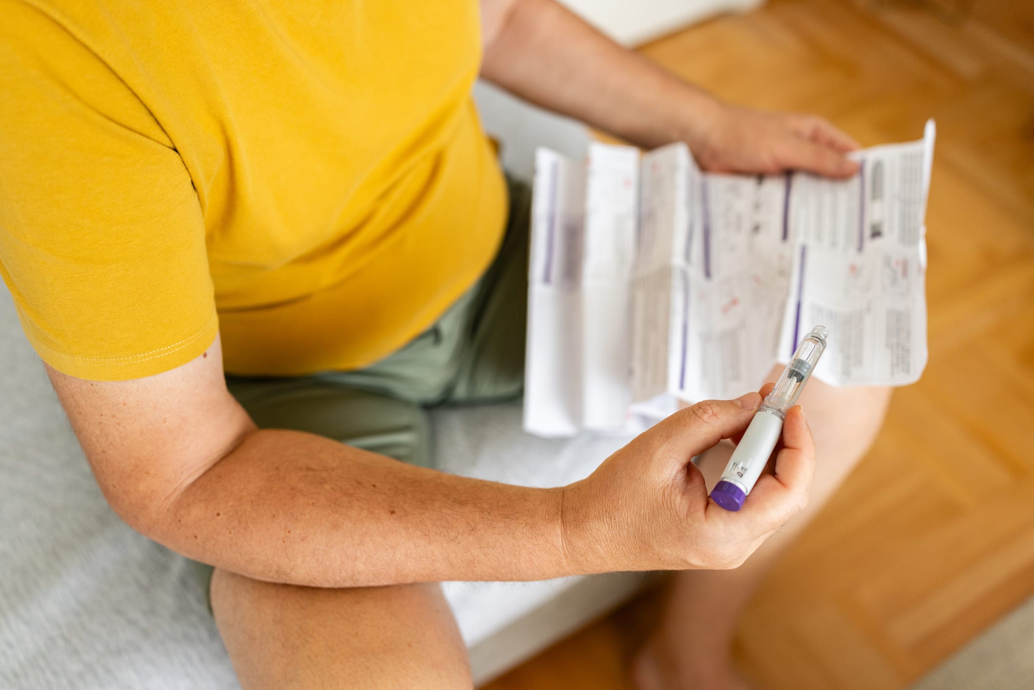 A person prepares to administer a GLP-1 medication for weight management, carefully reviewing the accompanying patient information leaflet