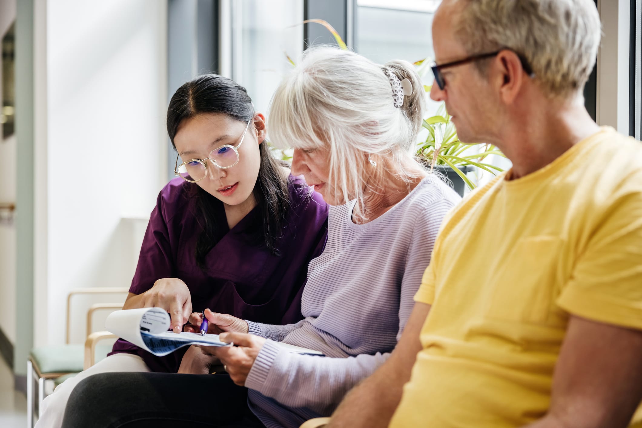 A nurse helping man and woman look at medical information