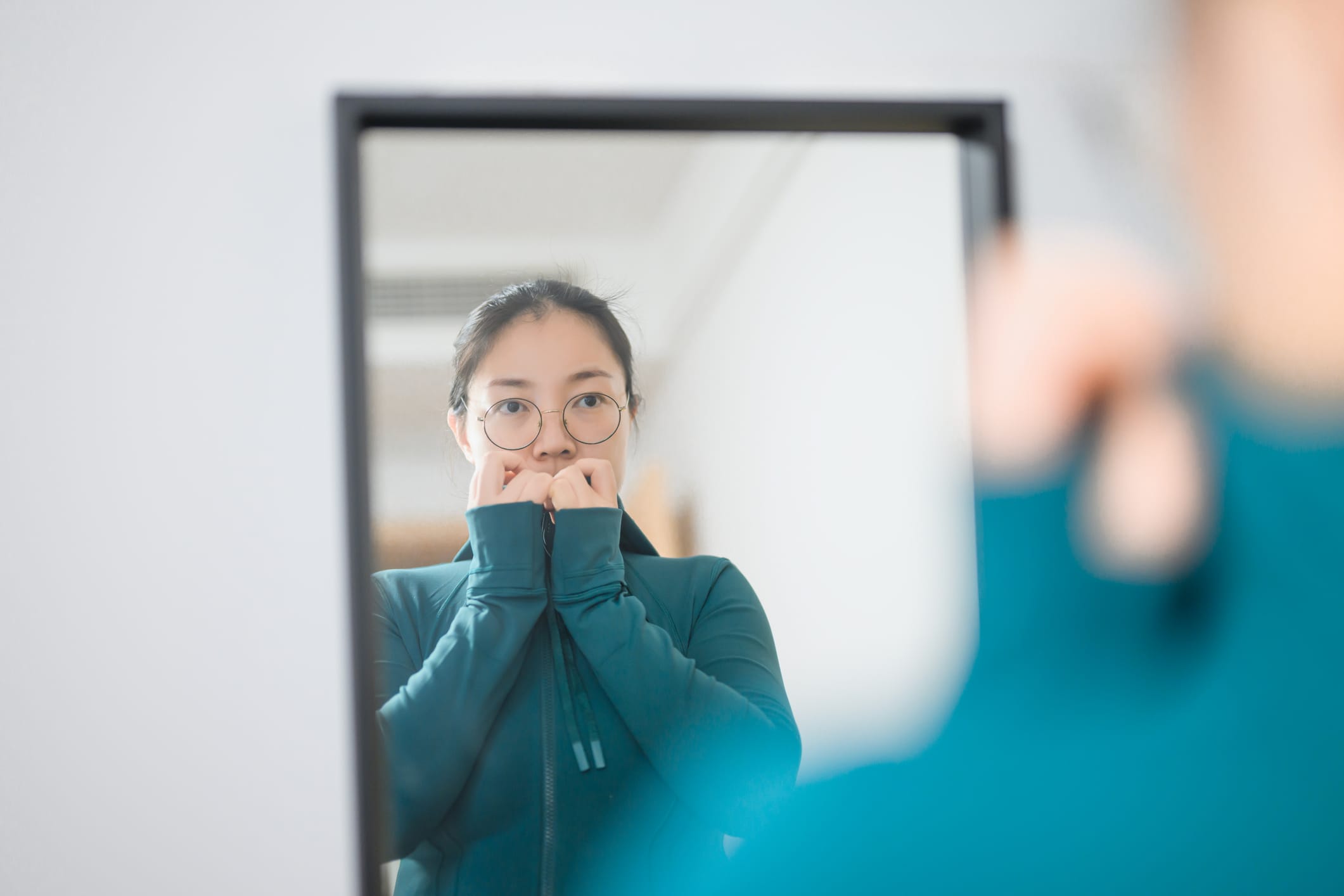 An Asian woman is looking in the mirror