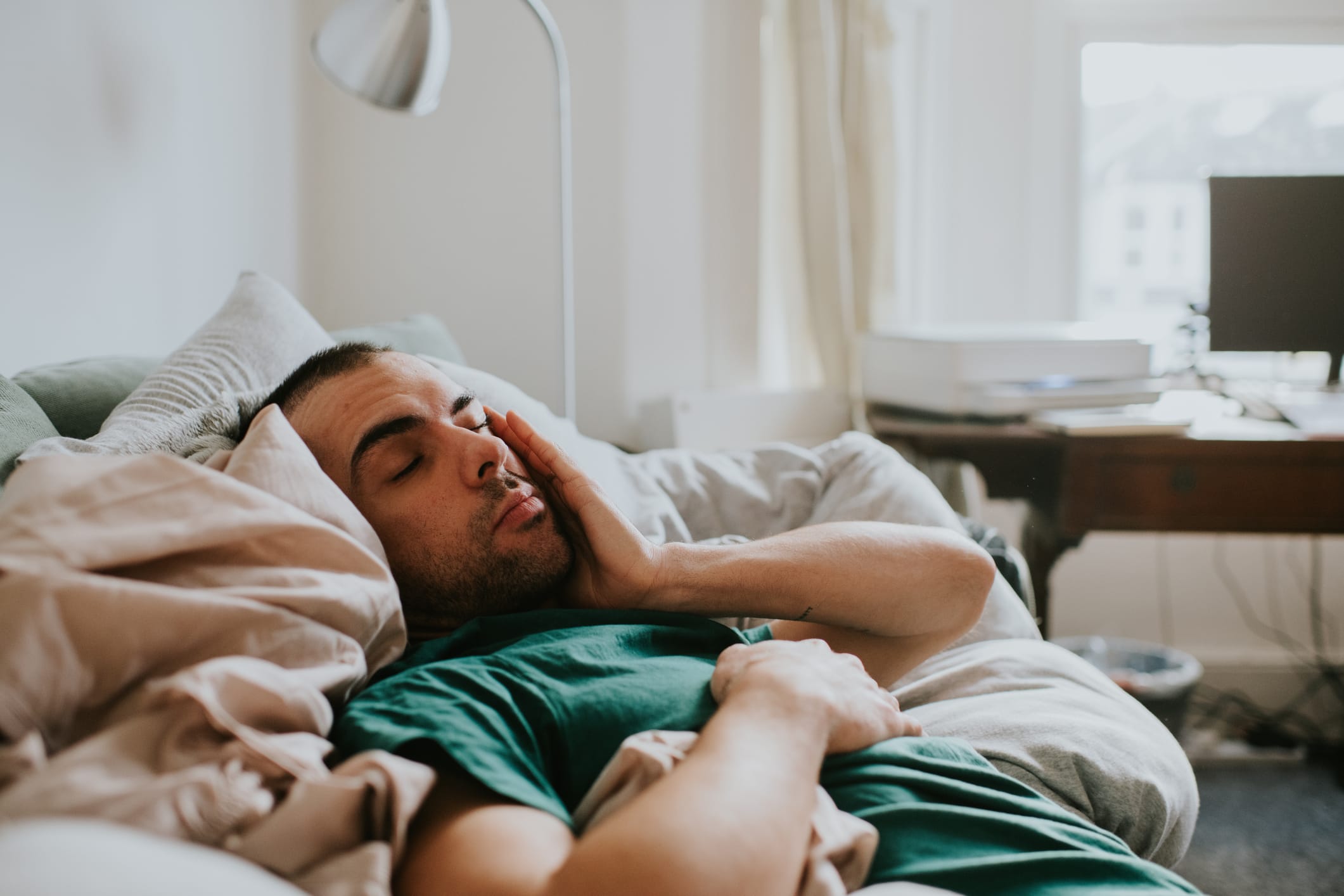 A man has just woken up rubbing face with hand