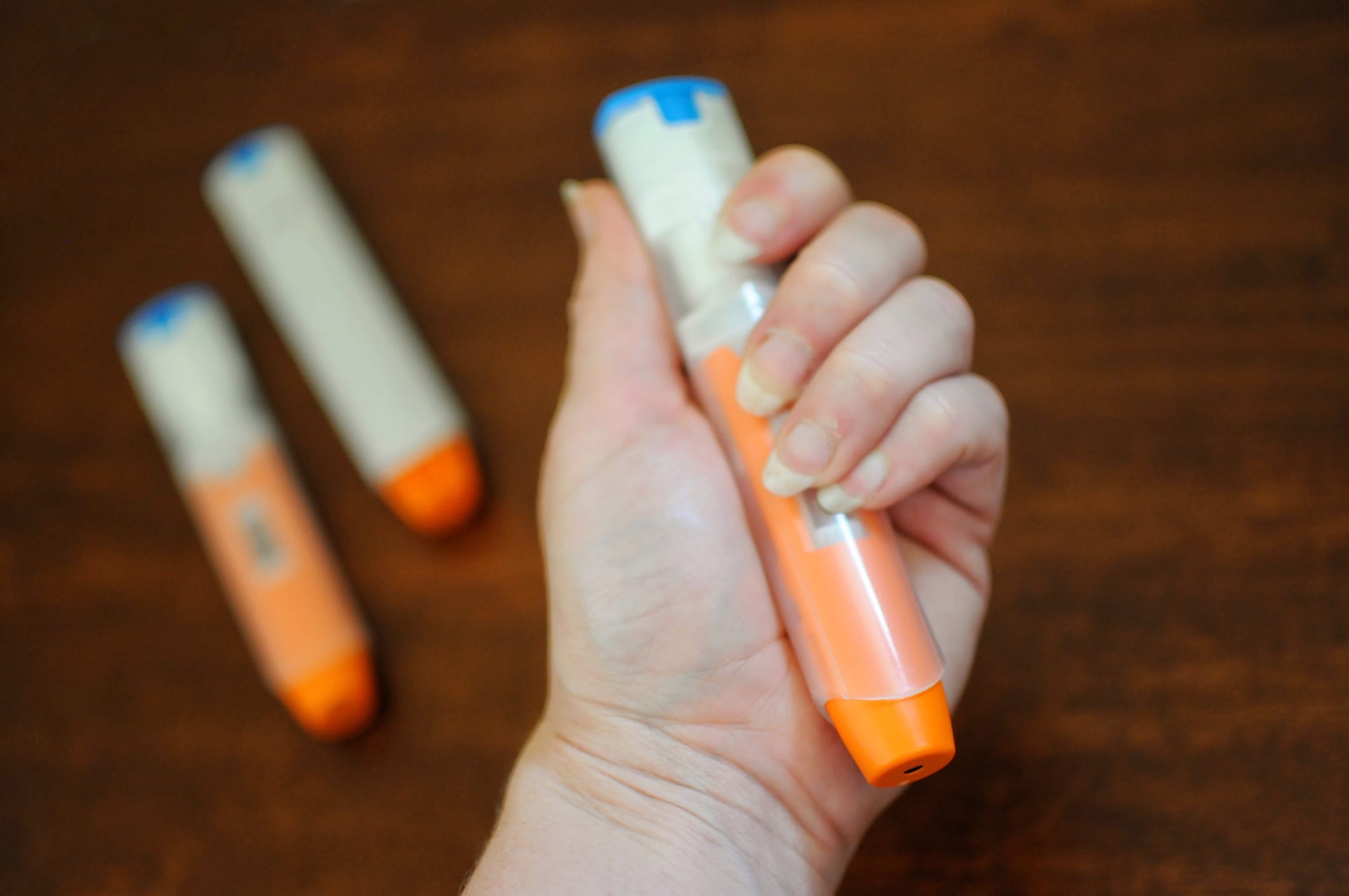 Woman’s hand holding a unused epinephrine Auto injector. The device is commonly used to treat the life threatening immune response known as anaphylaxis.