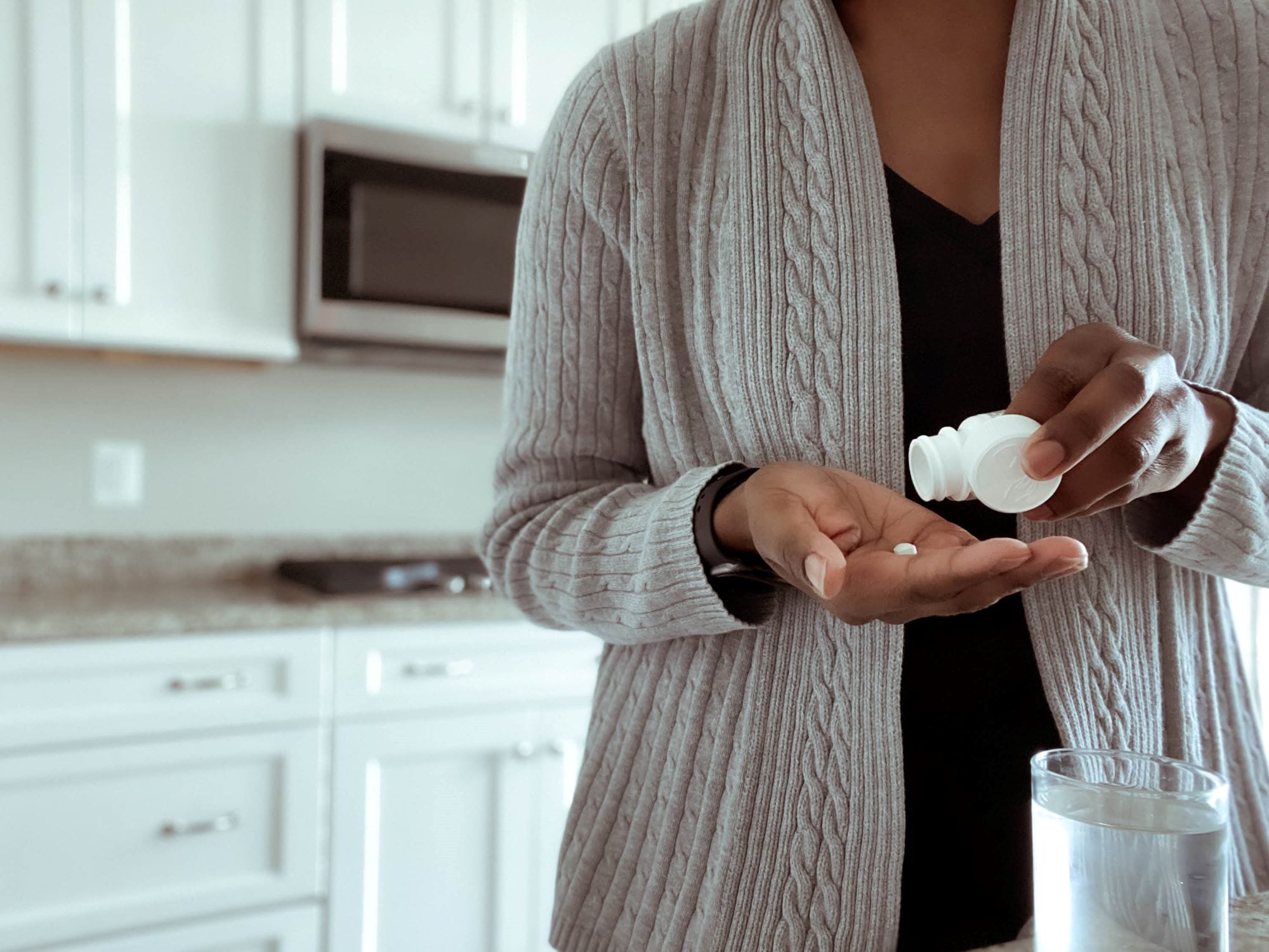 lose-up of unrecognizable woman pouring pills into palm of hand